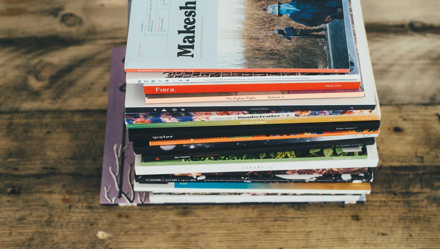Pila de revistas coloridas sobre una mesa de madera.