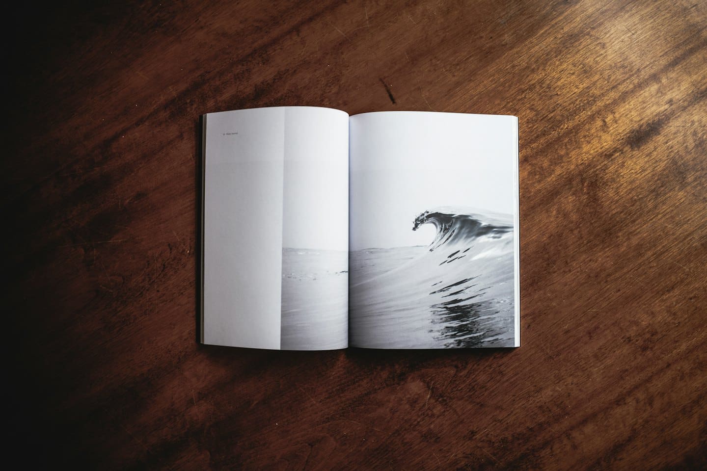 Revista abierta sobre mesa de madera oscura con foto de ola de mar.