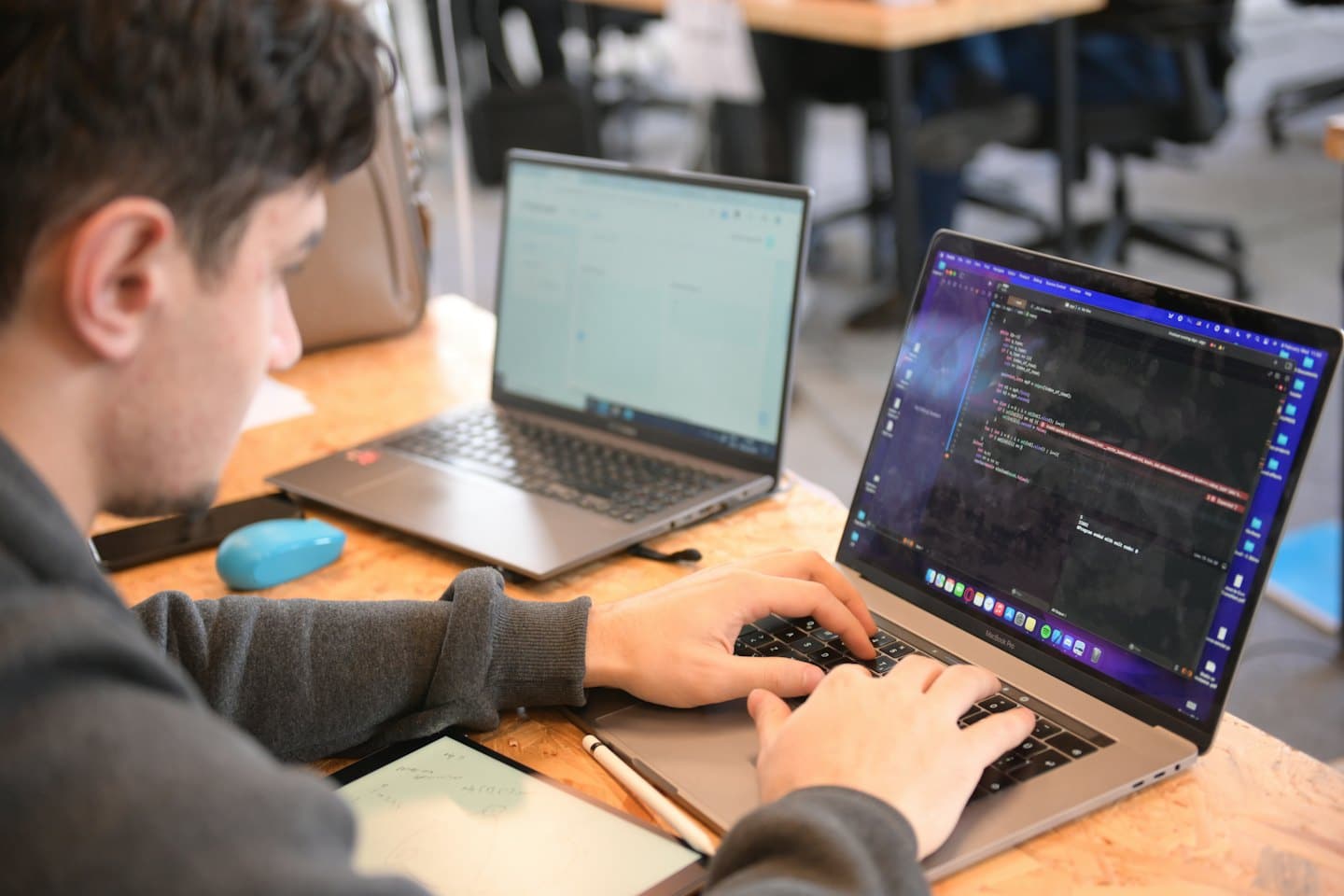 Un hombre escribe código de programación en un portátil sobre un escritorio.